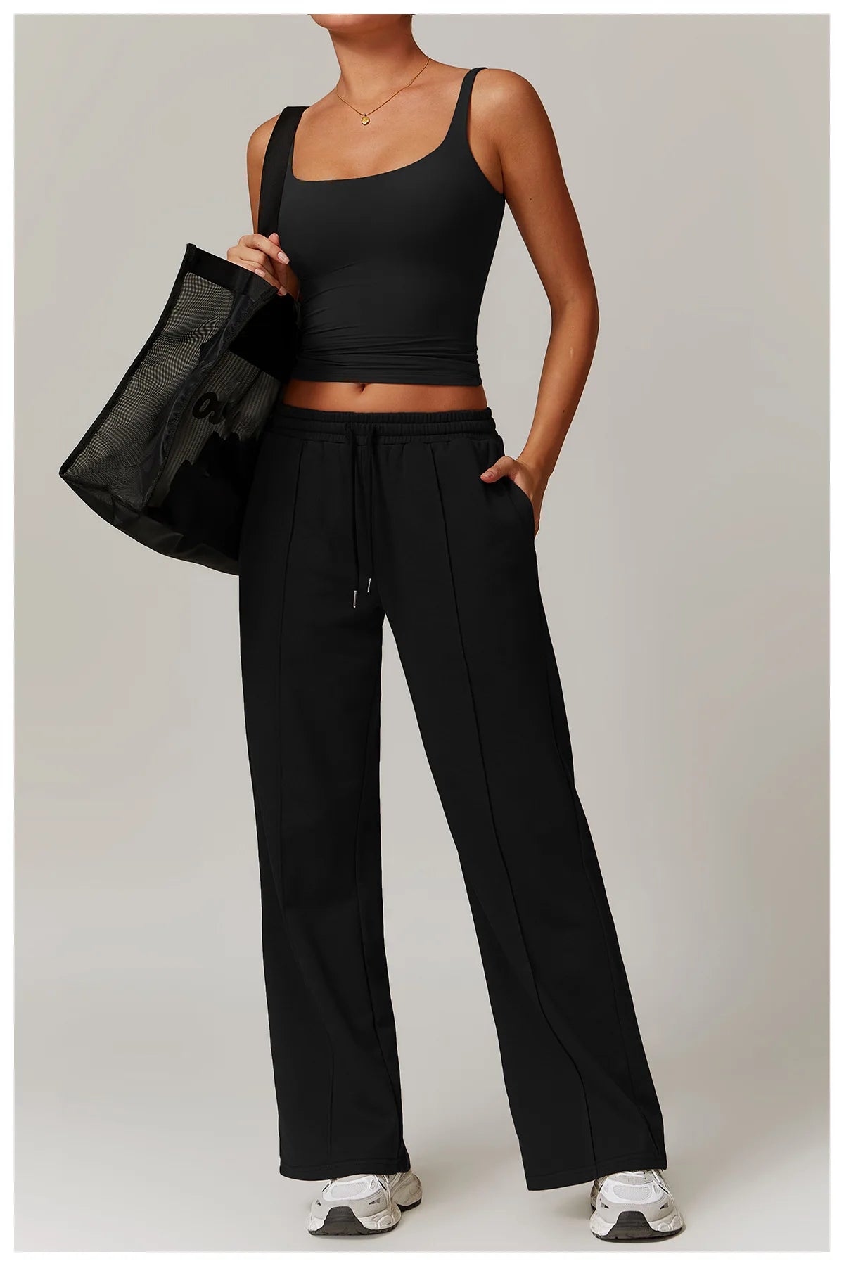 Black fitted tank top worn with wide leg trousers, full length