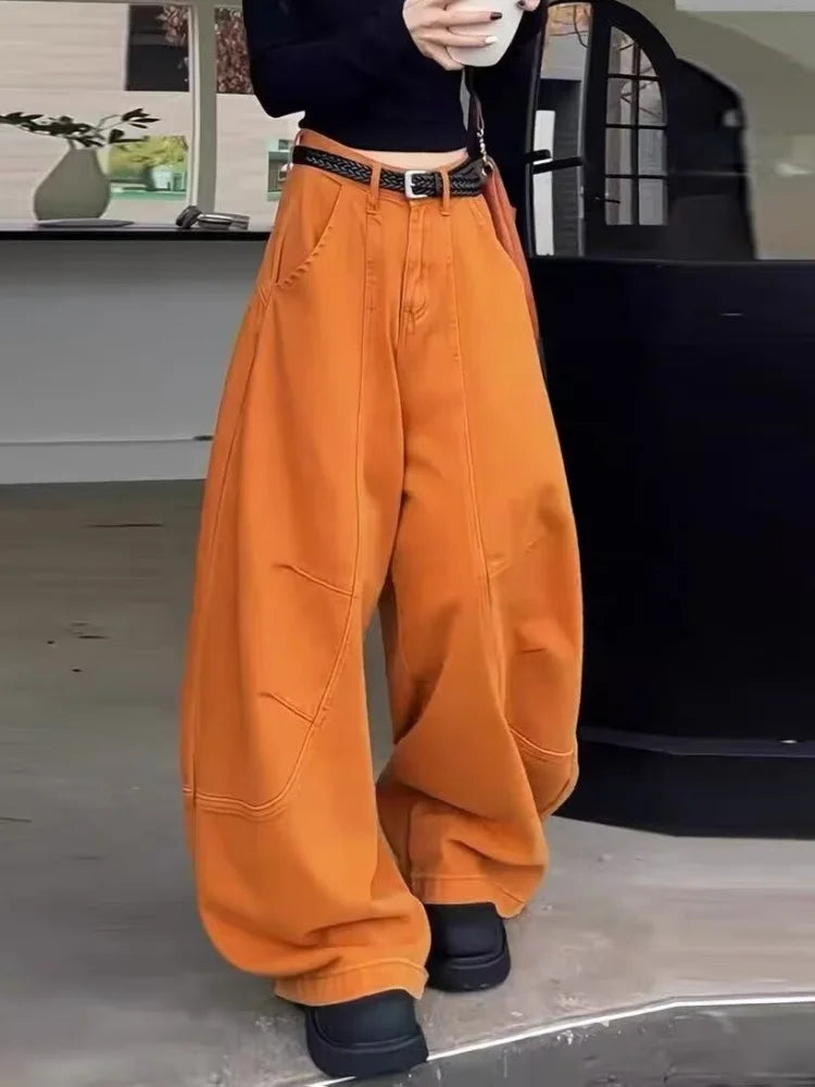 Orange barrel pants for women, front view, worn with black fitted top and boots