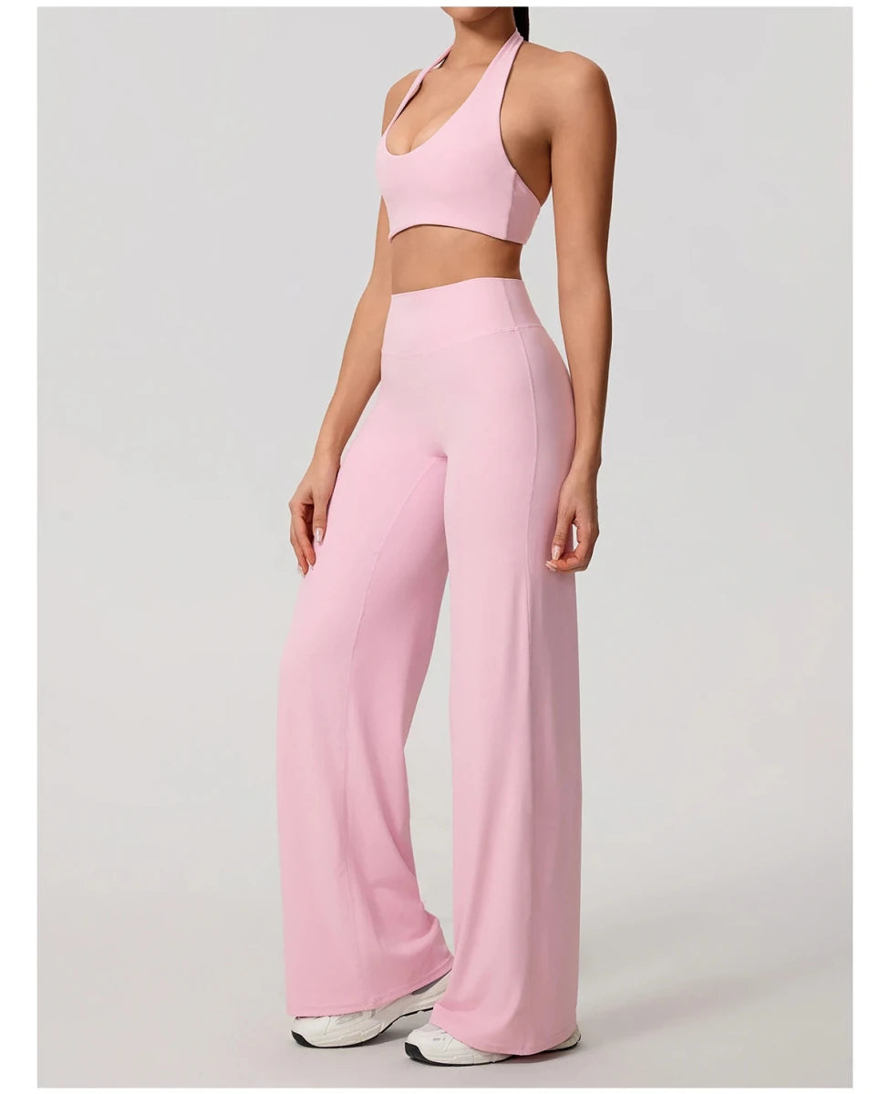 Peach pink pilates outfit with open back halter bra and wide leg trousers, front, hand raised